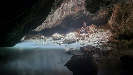 A view from inside La Cueva de las Sardinas, where light from an opening above shines on the light blue water