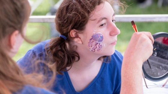 University of Missouri–St. Louis junior history major Em Carmichael check out the facepaint design during the Mirthweek Carnival.