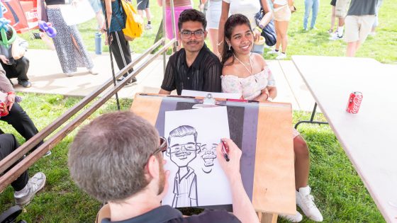 University of Missouri–St. Louis graduate students Pavani Laxmi Priya Maheswarapu and Sujith Sudagani get a caricature done during the Mirthweek carnival.