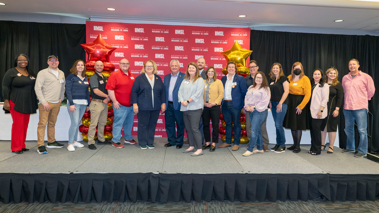 UMSL employees marking their five-year anniversaries stand on stage in the Century Rooms of the Millennium Student Center