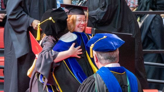 Accounting graduate Angela Truesdale hugs College of Business Administration Dean Shu Schiller as she walks across the stage