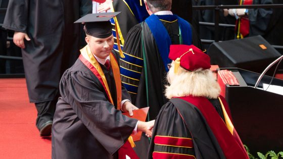 Graduate Grant Ebert, the outstanding student in accounting, shakes hands with Chancellor Kristin Sobolik during Saturday's ceremony.