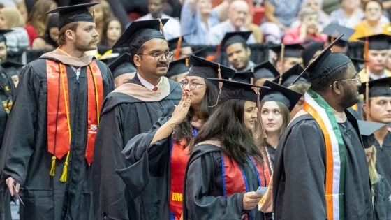 Supply chain and analytics master's student Kabita Rokka blows a kiss toward someone in the crowd while processing into the Mark Twain Athletic Center for Friday night's ceremony celebrating graduates of the College of Business Administration and UMSL/Washington University Joint Undergraduate Engineering Program