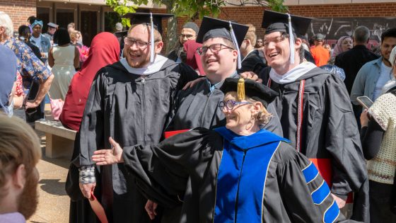 Department of History Chair Laura Westhoff takes photos with three new graduates Saturday afternoon