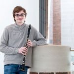 Jake Philipak holding his clarinet in the lobby of the Blanche M. Touhill Performing Arts Center