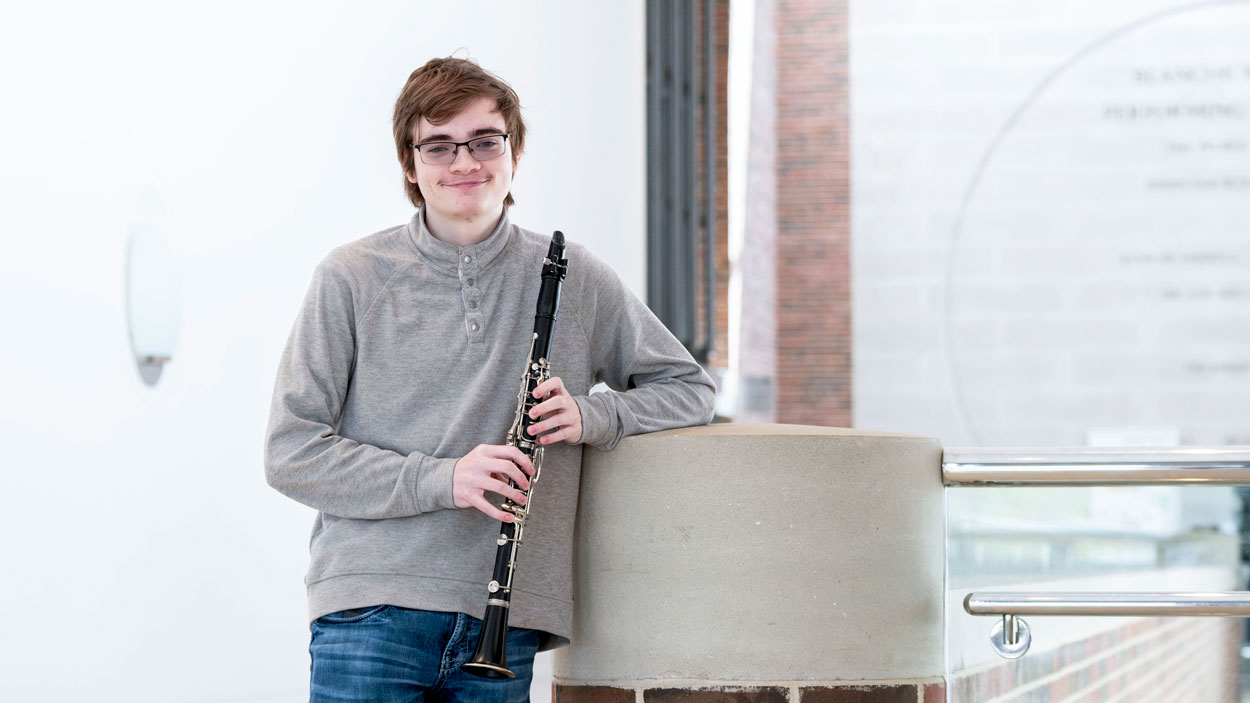 Jake Philipak holding his clarinet in the lobby of the Blanche M. Touhill Performing Arts Center