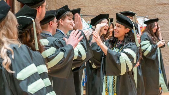 College of Optometry graduate Dr. Tiffany Aldridge-Rhine high-fives and congratulates classmates before the start of Friday's ceremony.
