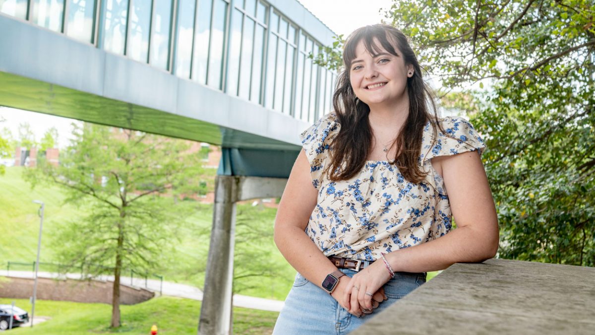 Sophie Heinz standing in front of the MSC Bridge on UMSL's North Campus