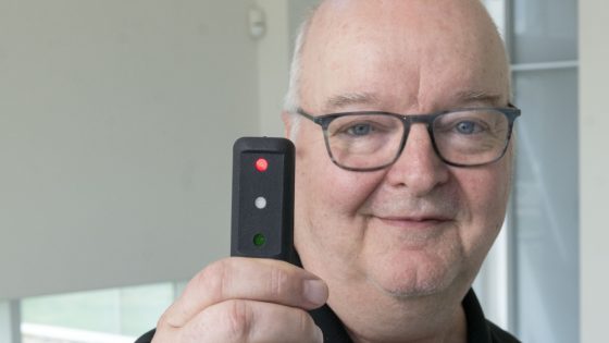 Curators' Distinguished Teaching Professor Carl Bassi holds up the Quantitative Three Dot test device