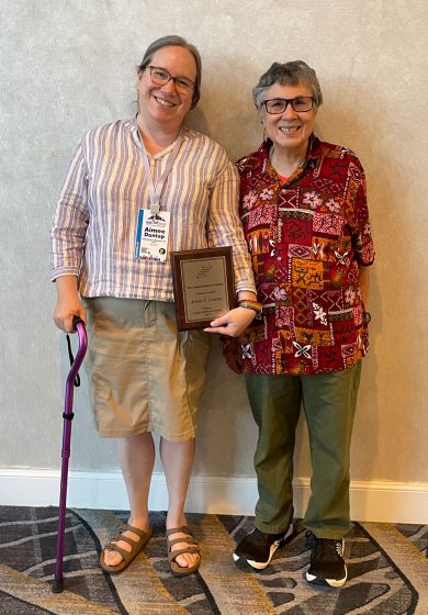 Aimee Dunlap holds plaque recognizing her as a Animal Behavior Society Fellow while standing with colleague Zuleyma Tang-Martinez