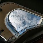 Clouds passing over the Recreation Wellness Center as seen from the bottom of the stairway outside the building