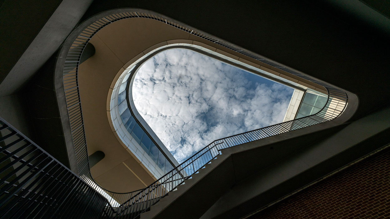 Clouds passing over the Recreation Wellness Center as seen from the bottom of the stairway outside the building