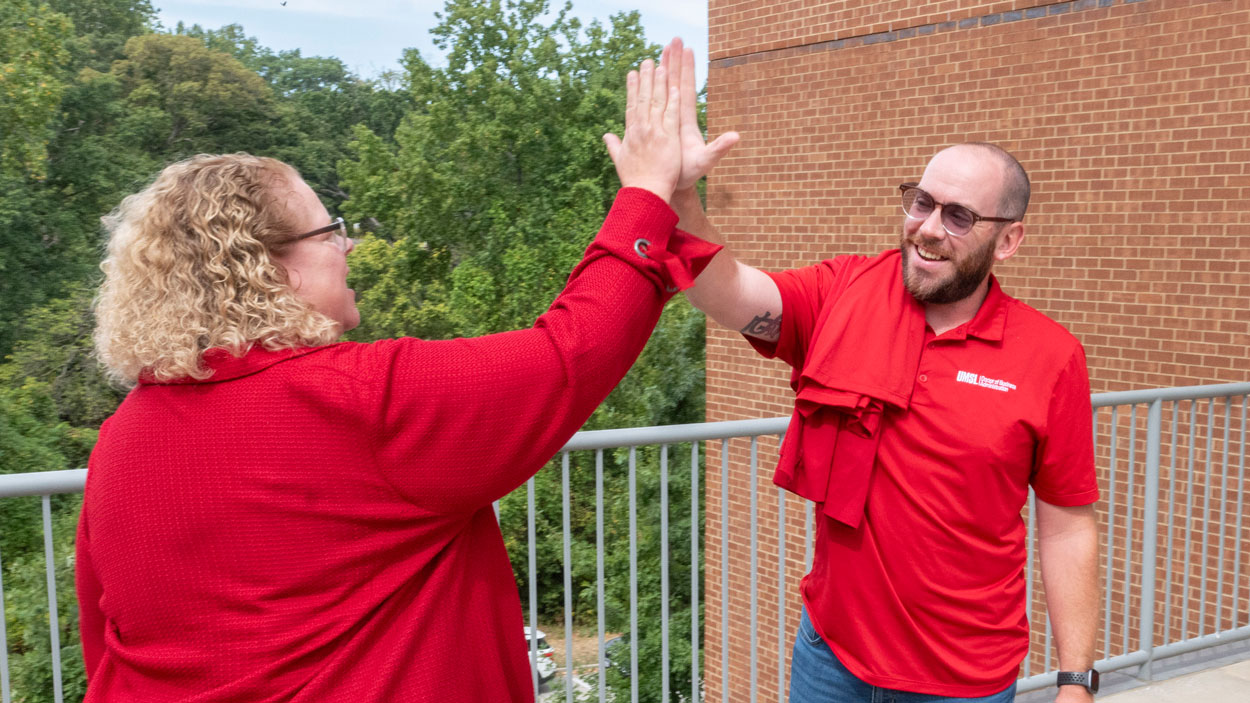 UMSL Chancellor Kristin Sobolik high fives Ed G. Smith College of Business senior academic advisor Justin Rubin