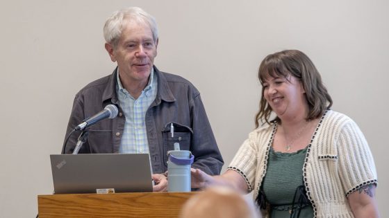 Professor Eamonn Wall and Kathleen Jochman stand near the lectern during an opening reception for Jochman's photo exhibit