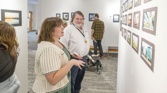 Kathleen Jochman talks to University City Public Library staff member David Bowser about some of the photographs on display from her summer study abroad trip to Galway, Ireland
