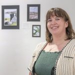 UMSL history major Kathleen Jochman stands in front of photos from her study abroad trip that are on display in the second-floor gallery at the University City Public Library