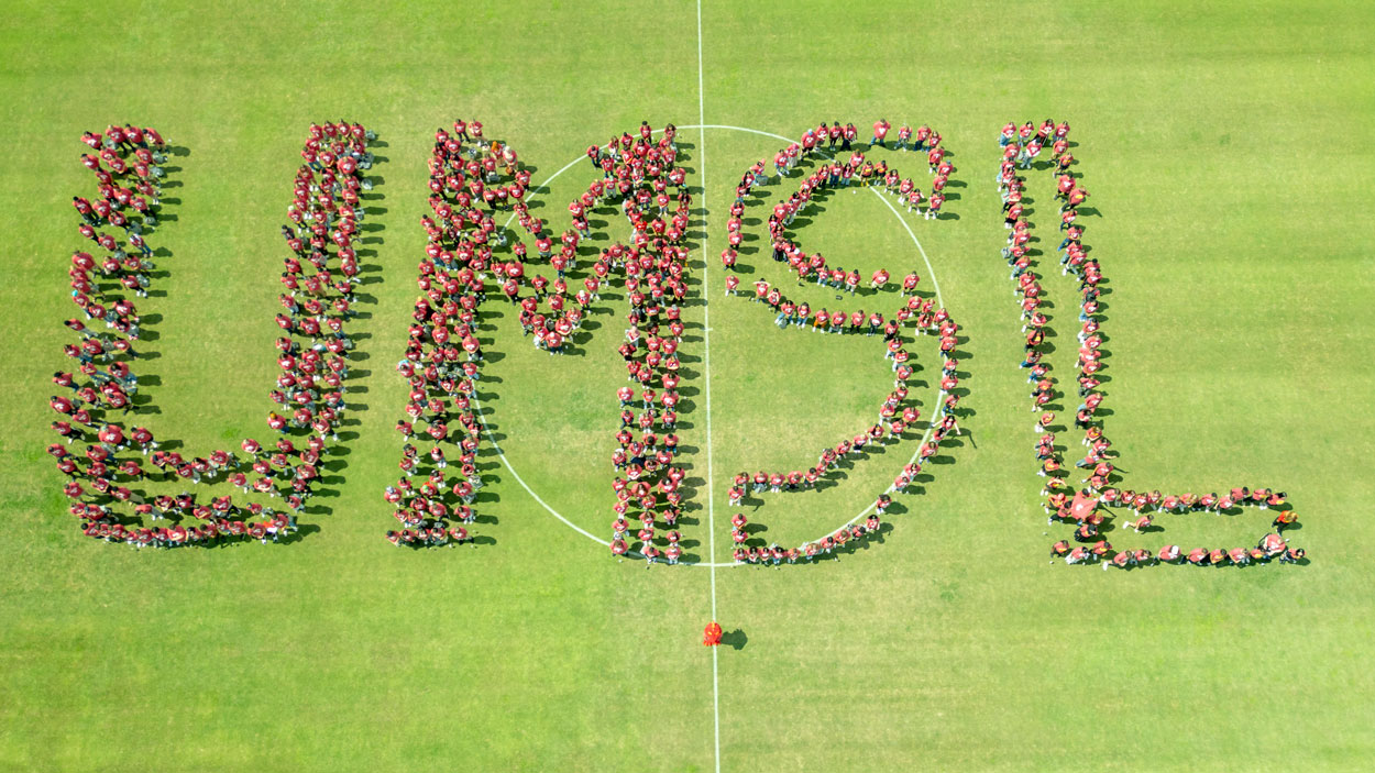 UMSL freshmen pose for a group photo in the shape of UMSL on the soccer field on Aug. 22, 2025