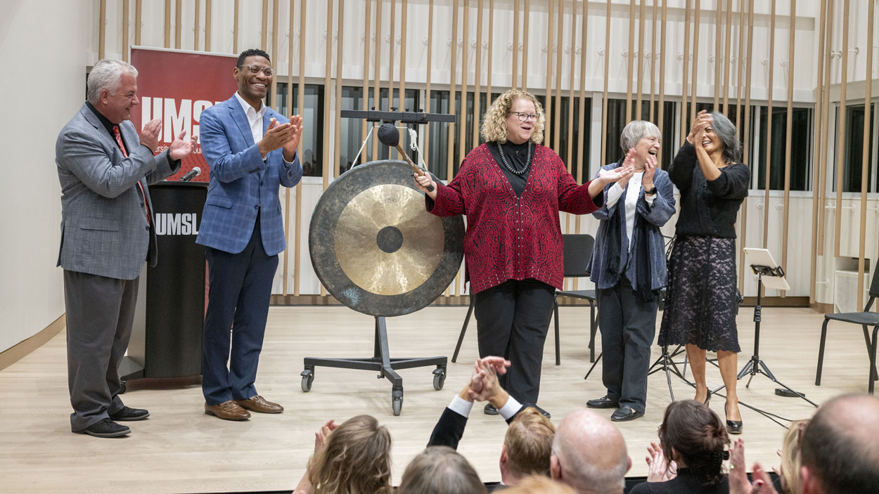 Chancellor Kristin Sobolik bangs a gong to signify the opening of UMSL's new Creative Arts Building on Tuesday night during an open house in the newly renovated space. She was joined on stage by (from left) Provost Steven J. Berberich, Sen. Brian Williams, Associate Professor Pamela Stuerke and Professor Joanna Mendoza.