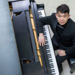 Eric Zhang looks up while seated at a grand piano