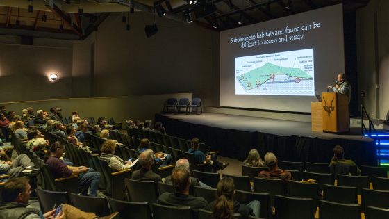 Matthew Niemiller presenting to a large audience during the Whitney and Anna Harris Conservation Forum
