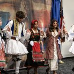 Greek dancers perform in front of a recreation of Rip Kastaris' mural "Kyklos – Circle of Glory"