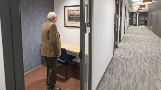 A visitor inspects a piece of art from the St. Louis Mercantile Library collection now hanging in one of the individual study rooms in the Thomas Jefferson Library