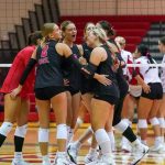 Members of the UMSL volleyball team huddle near the net as they celebrate a point