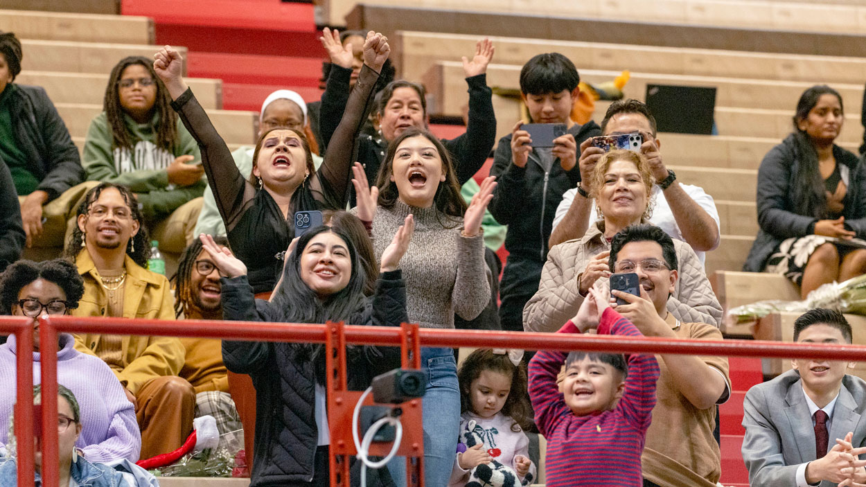 Family and friends of graduate Kimberly Barrera Gonzalez cheer her on as she walks across the commencement stage