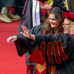 Accounting graduate Alex Paubel and Chancellor Kristin Sobolik wave to Paubel's family during commencement