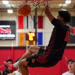 UMSL men's basketball player Vincent Davis III hangs from the rim after dunking the ball against Maryville