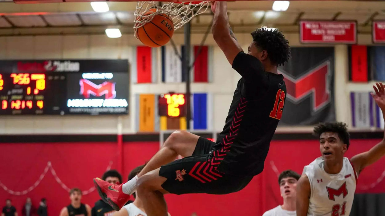 UMSL men's basketball player Vincent Davis III hangs from the rim after dunking the ball against Maryville