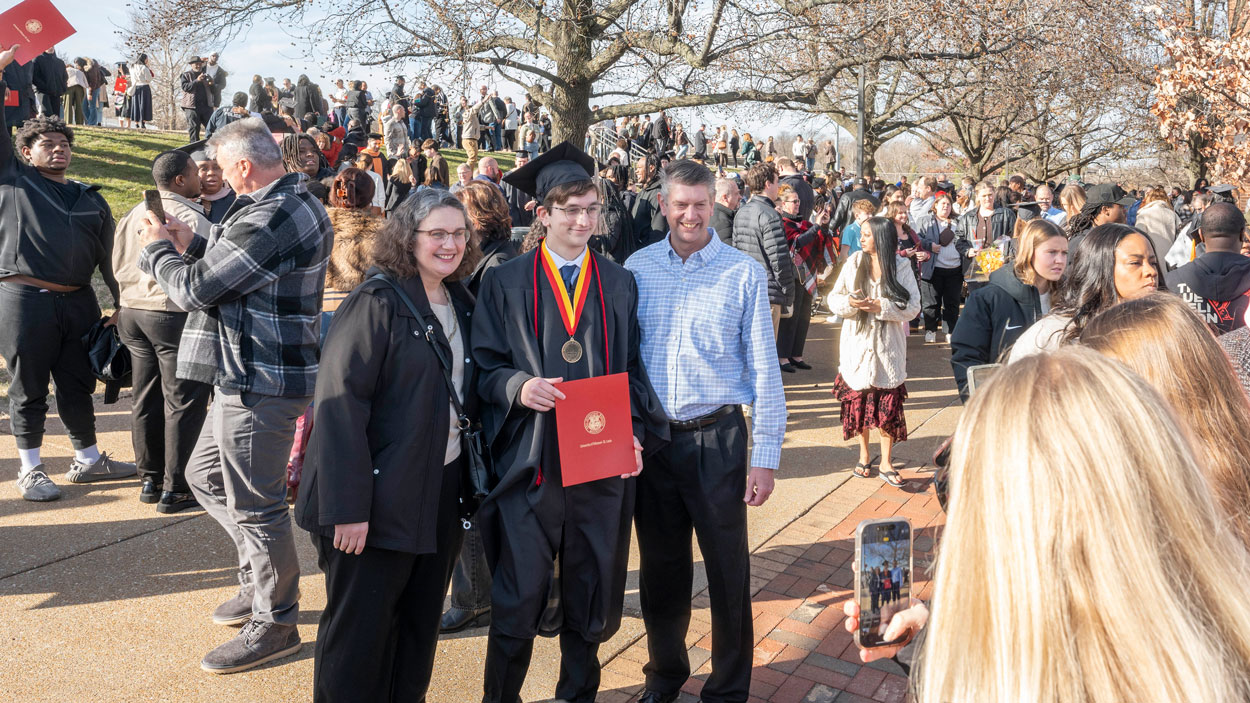UMSL graduates take advantage of the unseasonably warm December day to pose with family and friends outside of Mark Twain.