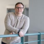 Master's in cybersecurity graduate Jarad Perry leaning against a railing