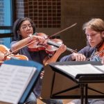 Professor Joanna Mendoza plays the viola while surrounded by UMSL students