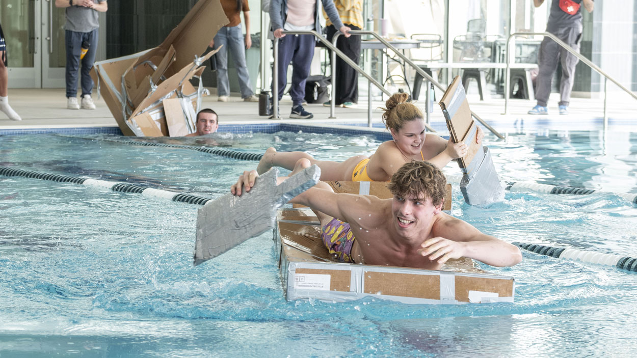 Sophomore electrical engineering major Mattia Nardi takes off in the lead in the UMSL Recreation and Wellness Center's Cardboard Boat Racing event while Chiara Alberola gives chase and Paul Williams sinks on March 12