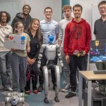 Professor Xin Wang (at right) and electrical engineering students show off their work with humanoid and quadruped robots