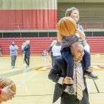 Leonid Pugachev, an assistant professor of finance, puts his son on his shoulders to help him attempt a shot at the basketball hoop at the Mark Twain Athletic Center during "Bring a Child To Work Day" on April 23