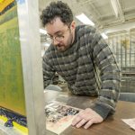 UMSL studio art major Jacob Jeliti lines up the paper while working on a on a two-layer silk screen project in the print making studio in the UMSL Fine Arts Building.