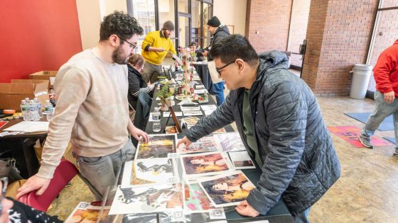 Studio art major Jacob Jeliti talks with CJ Sunega, a staff member in the Department of Psychological Sciences, about his screen prints during a Winter Market held in December in Lucas Hall.