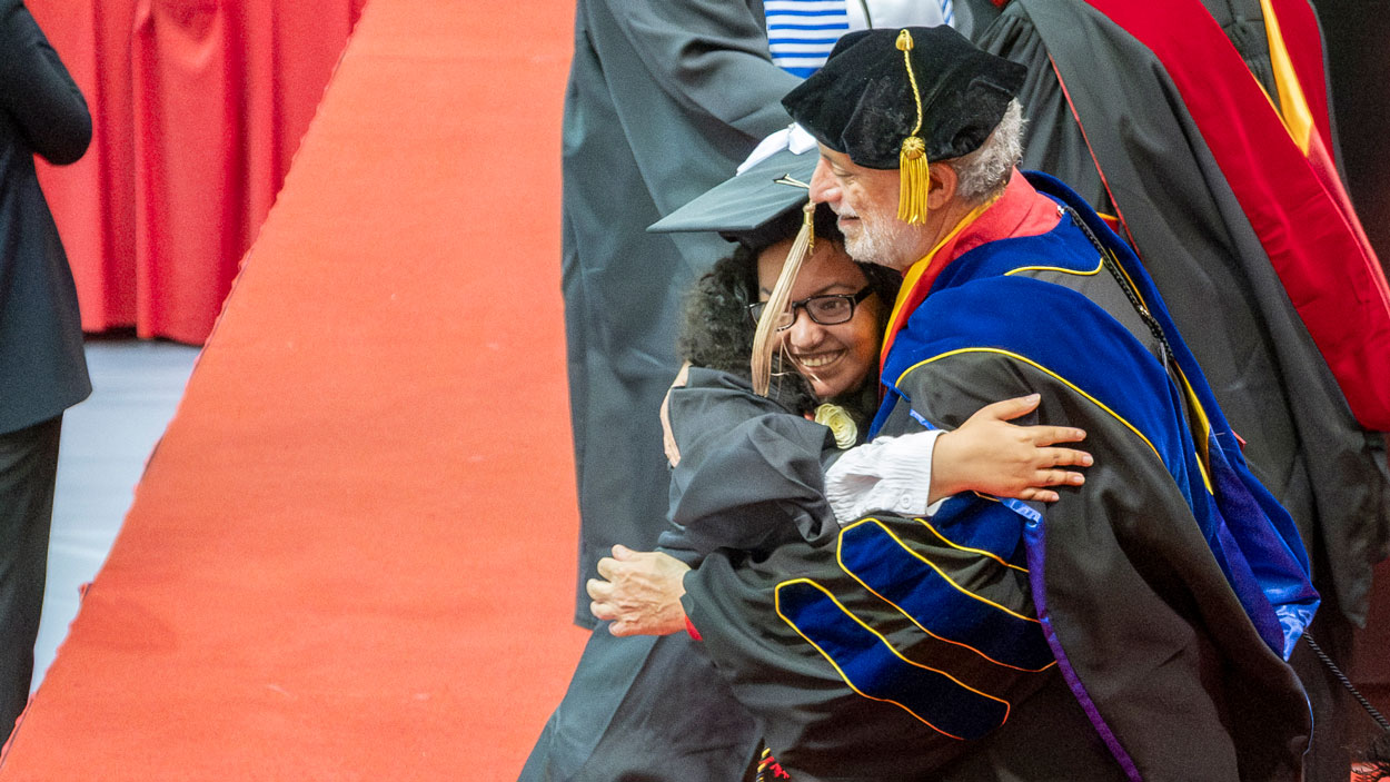 UMSL accounting and Honors graduate Kara Johnson hugs Pierre Laclede Honors College Dean Edward Munn Sanchez during commencement.