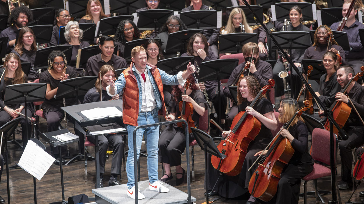 Musicians at the University of Missouri–St. Louis chuckle as Assistant Teaching Professor David Wacyk takes the stage dressed up as Marty McFly, Michael J. Fox's famous character from the classic 1985 movie "Back to the Future," to conduct the UMSL Symphony Orchestra and Wind Ensemble's end-of-semester concert, "UMSL at the Movies," on May 13 in the Blanche M. Touhill Performing Arts Center.