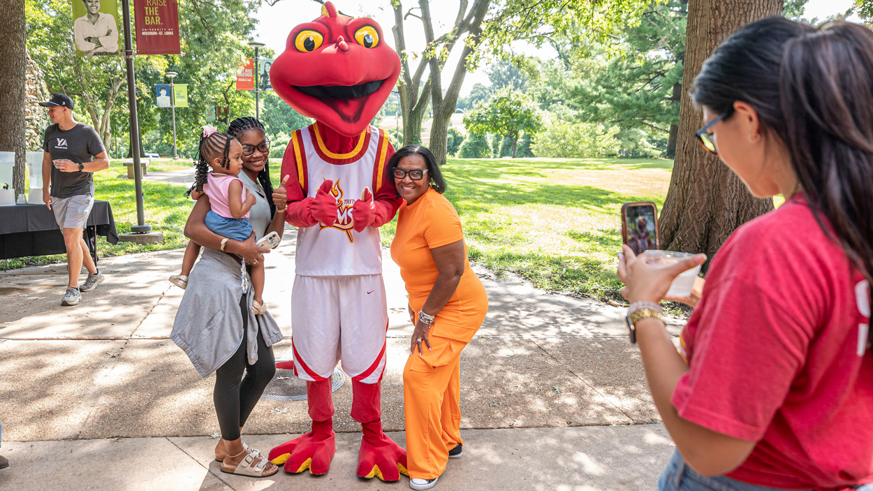 UMSL spanish major Nashara Flowers, from the Bahamas, holds her godchild La'Shante Rolle as she poses for a photo with UMSL Mascot Louie and her mother Vonetta Darling during move in day.