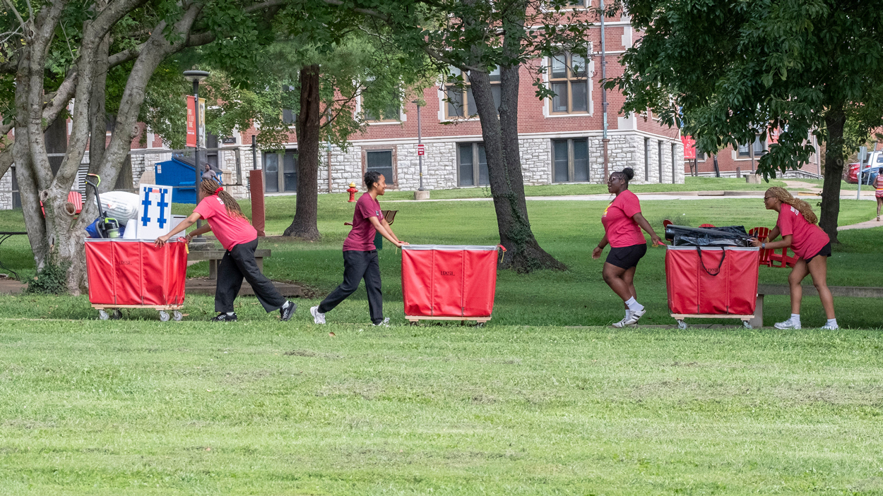 Volunteers push red roller carts to Oak Hall