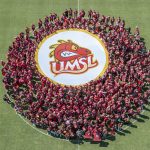 First-year students at the University of Missouri–St. Louis huddled together at the middle of the Don Dallas Soccer Field on Friday afternoon during New Student Orientation and showed off a Louie the Triton logo as UMSL photographer Derik Holtmann used a drone to capture their photo from overhead.