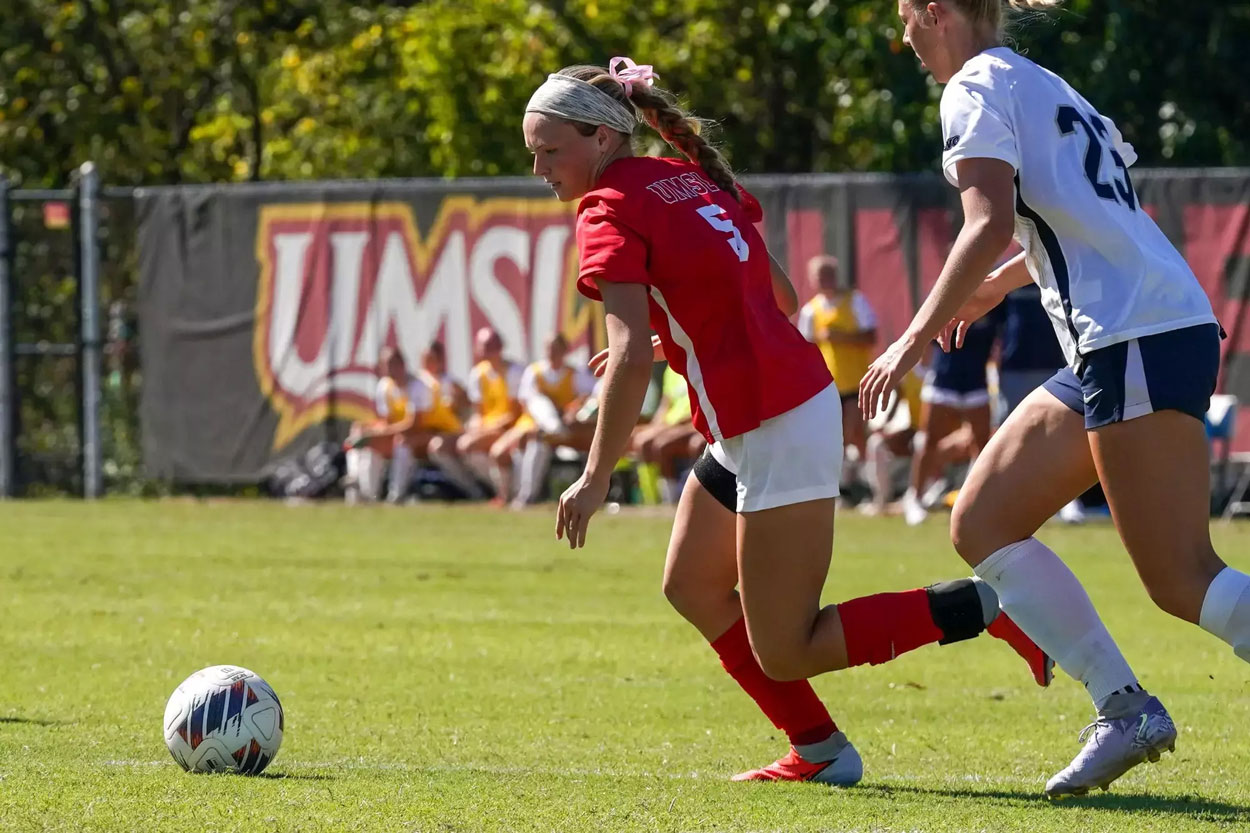 UMSL women's soccer player Josie Maddox dribbles while being hounded by an Illinois Springfield defender