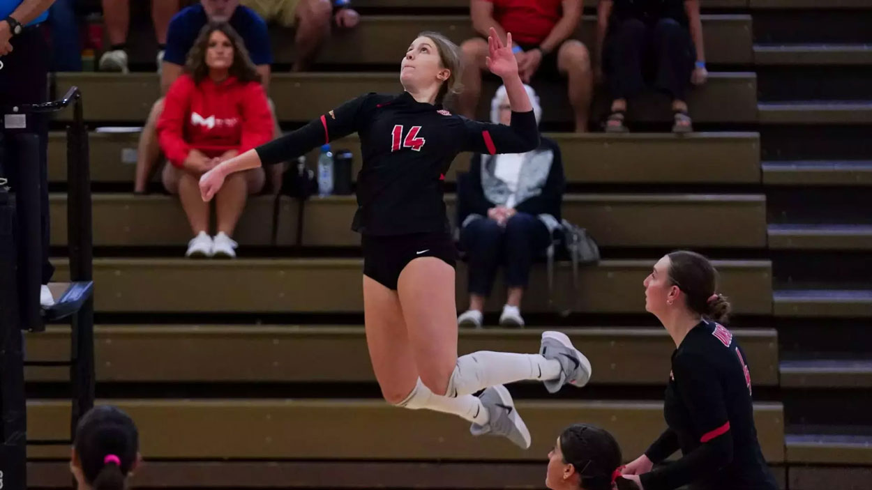 Alayna Santel jumping to spike a volleyball