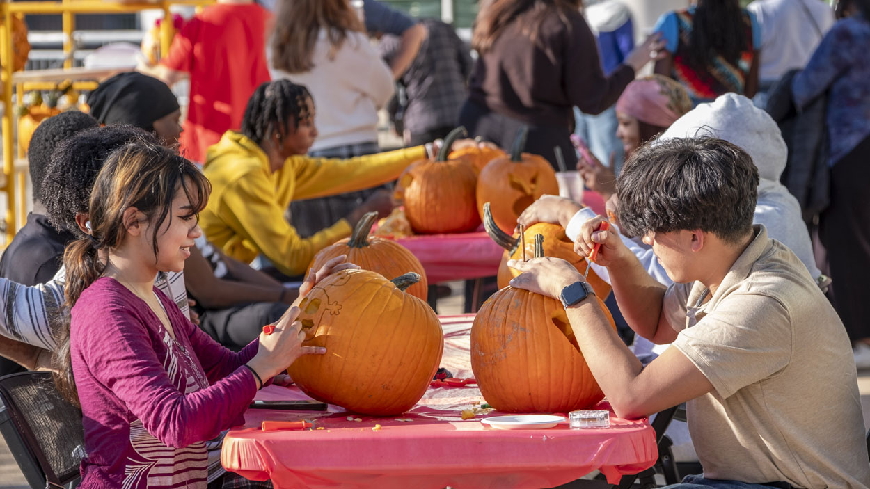 Sophomore criminology and psychology major Emily Batres and freshman business administration major Jackson Paiz Rodriguez carve pumpkins with other students outside the MSC