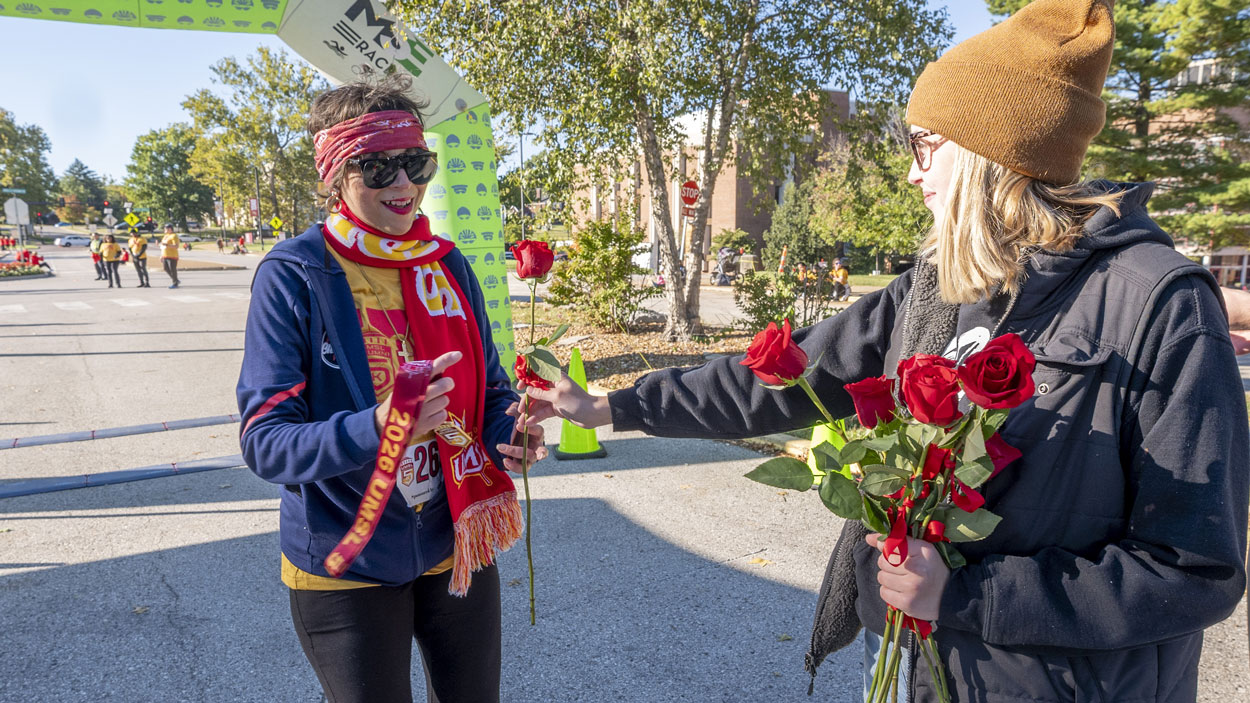 Senior Academic Advisor Antoinette Sterling receives a rose from junior sports management major Camilla Winkelman to go with her race medal after crossing the finish line