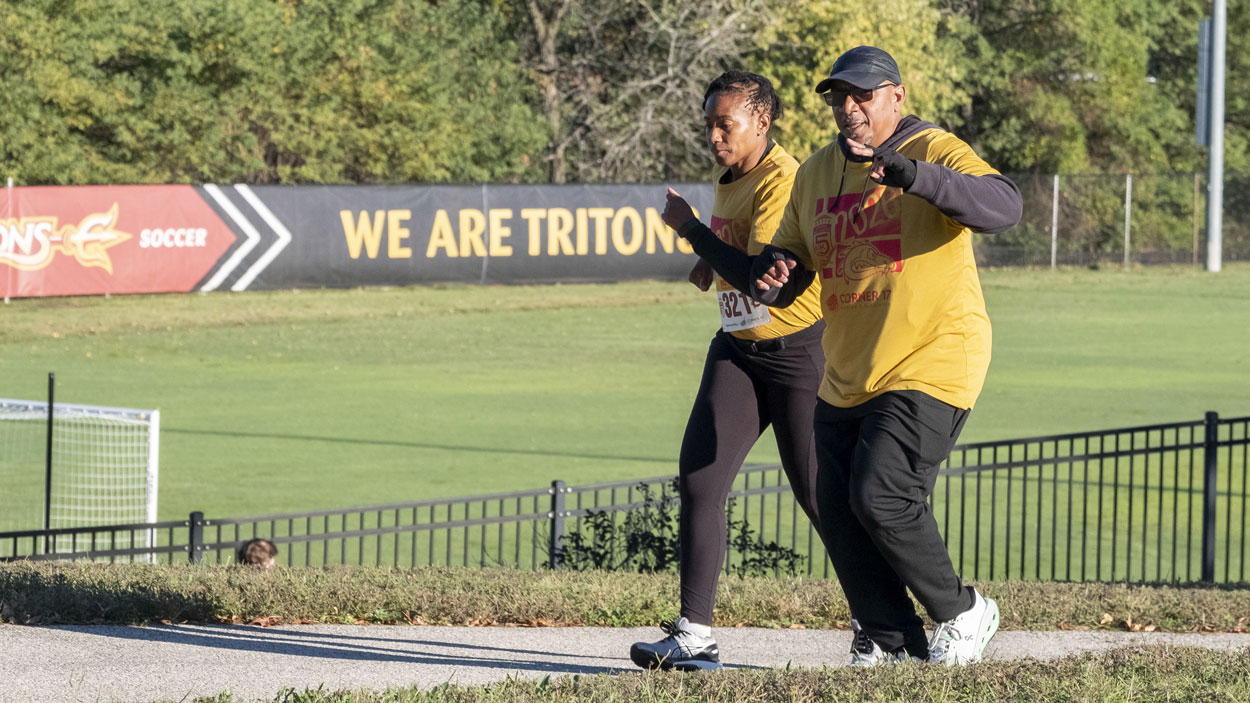 Alum Latonya Bowens and Assistant Teaching Professor Damon Walker run together past the Don Dallas Soccer Field during the UMSL 5K Run/Walk 