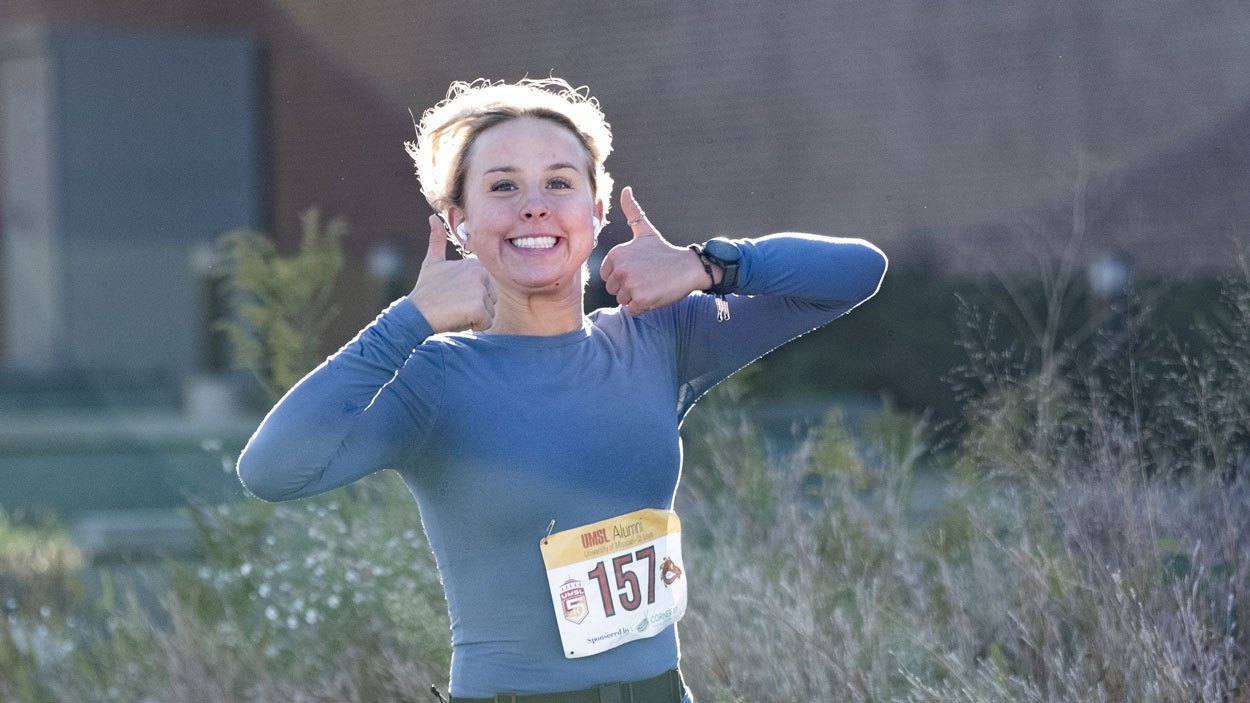 Biology student Saige Grassino gives two thumbs up while running in the UMSL 5K Run/Walk